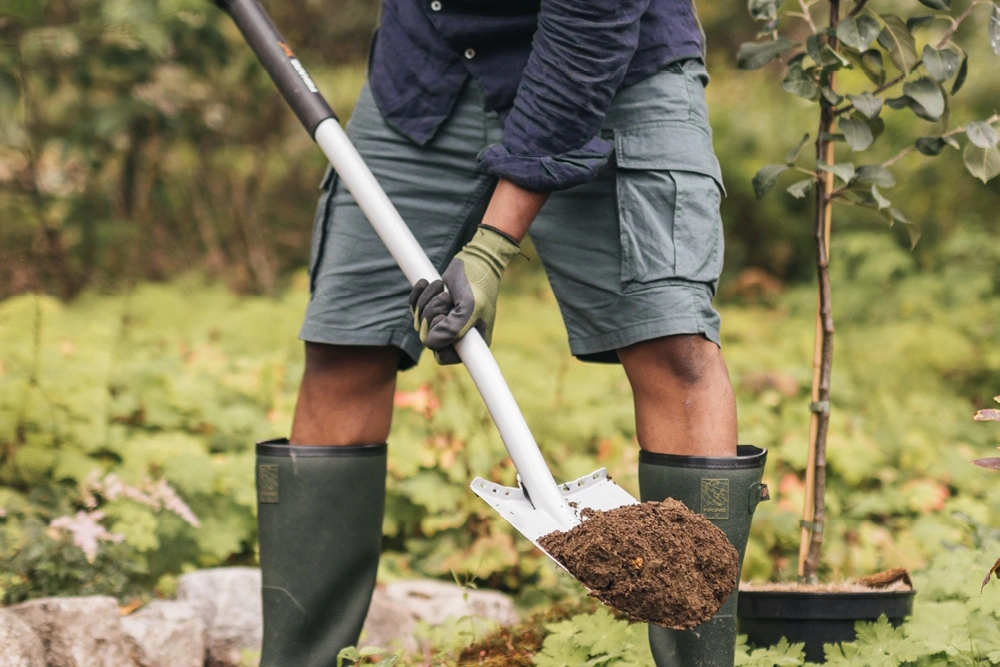 Eine Person nutzt eine Fiskars Schaufel im Garten